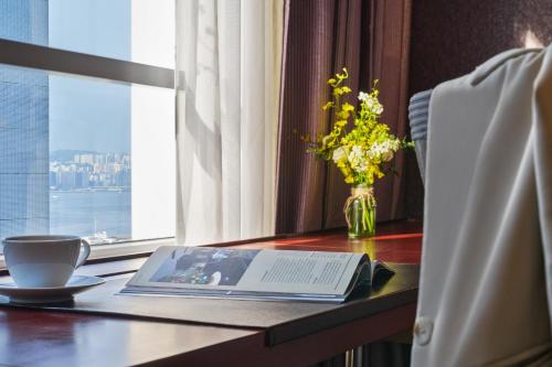 a table with a book and a vase with flowers on it at Novotel Century Hong Kong in Hong Kong