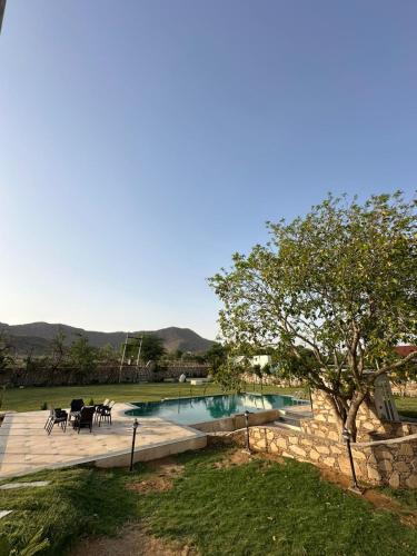 a pool with tables and chairs next to a yard at Tuscan Villa in Pushkar