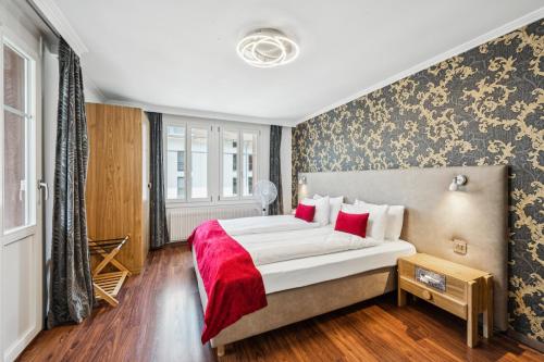 a bedroom with a large bed with red pillows at Hotel Sonne Interlaken-Matten in Interlaken