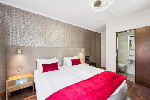a bedroom with a large bed with a red blanket at Hotel Sonne Interlaken-Matten in Interlaken
