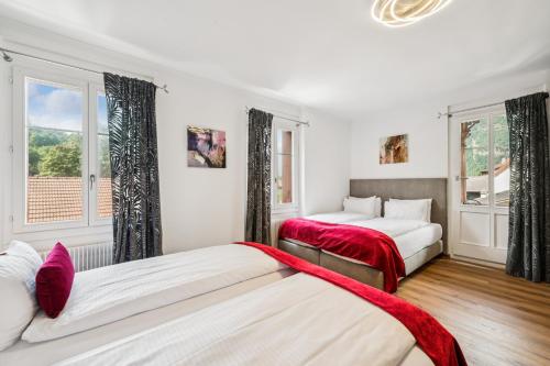 two beds in a room with two windows at Hotel Sonne Interlaken-Matten in Interlaken