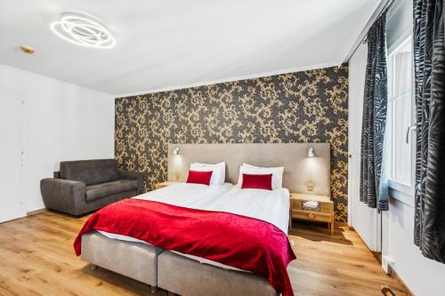 a bedroom with a bed and a chair at Hotel Sonne Interlaken-Matten in Interlaken
