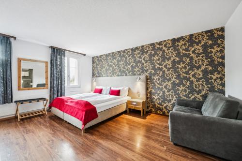 a bedroom with a bed and a couch at Hotel Sonne Interlaken-Matten in Interlaken