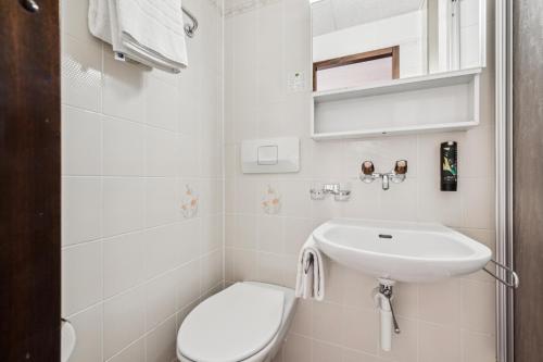 a white bathroom with a sink and a toilet at Hotel Sonne Interlaken-Matten in Interlaken