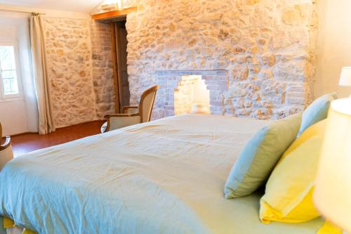 a large bed in a room with a stone wall at Domaine de la Cascade Parfumée in Grasse