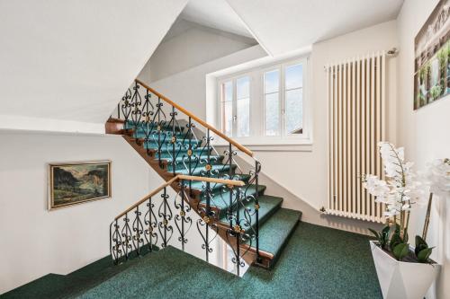 a staircase in a house with green carpet at Hotel Sonne Interlaken-Matten in Interlaken