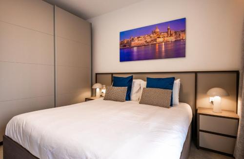 a bedroom with a large bed with blue pillows at Downtown Central Apartments in Msida