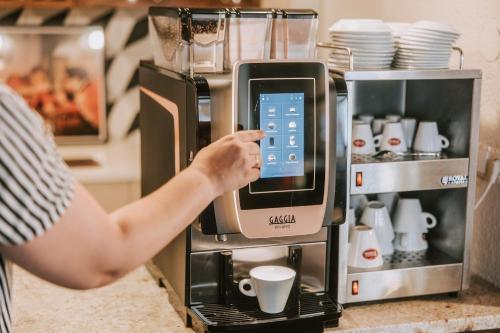 a woman is using an alka coffee machine at Velotique Hotel Angelika - Self-Check-in in Hard