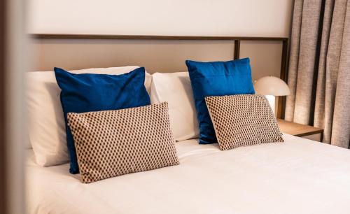 a bed with blue and white pillows on it at Downtown Central Apartments in Msida