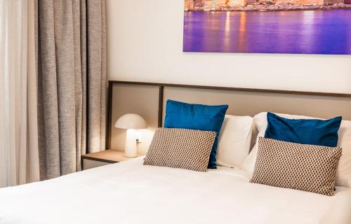 a bedroom with a white bed with blue pillows at Downtown Central Apartments in Msida