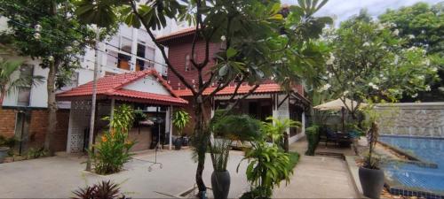 a house with a swimming pool and trees in front of it at Banksy's Siem Reap in Phumĭ Réach Born