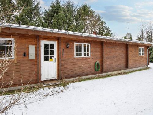 a wooden cabin with a white door in the snow at 6 person holiday home in Fårvang-By Traum in Fårvang