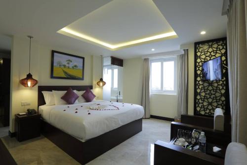 a bedroom with a large bed and a tv at River Suites Hoi An in Hoi An