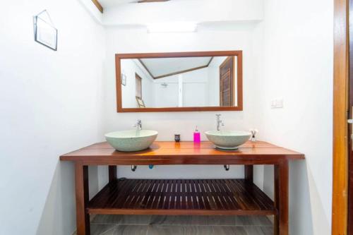 a bathroom with two sinks and a mirror at Banksy's Siem Reap in Phumĭ Réach Born