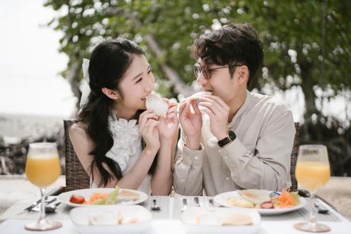 a man and woman sitting at a table eating food at Bintan Exotica Resort By WH - Free Shuttle BBT Resort BBT - Free Breakfast in Berakit