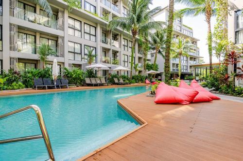 a swimming pool with red pillows next to a building at Diamond CONDO by VС in Bang Tao Beach