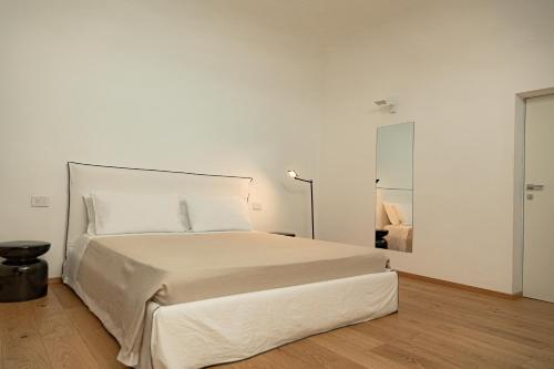 a white bedroom with a large bed and a lamp at Palazzo Console in Lecce