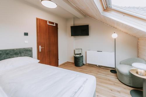 a bedroom with a bed and a chair and a television at Velotique Hotel Angelika - Self-Check-in in Hard