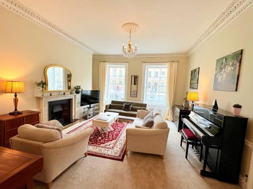 a living room with a couch and a piano at Large Quiet City Centre Holiday Home in Great Pulteney St, Bath in Bath