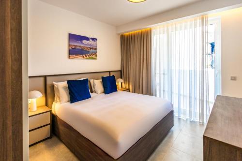 a bedroom with a large bed with blue pillows at Downtown Central Apartments in Msida