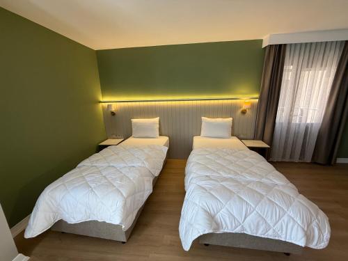 two beds in a room with green walls at OTTO X Hotel in Kavaklıdere