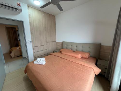 a bedroom with a bed with an orange comforter at Serenity Luna Suite at M Luna KL in Kuala Lumpur