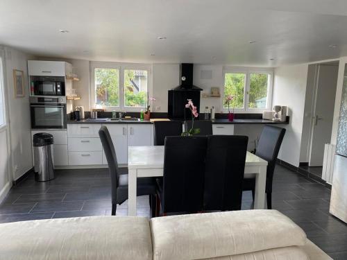 a kitchen with a white table and chairs and a table and a couch at Maison avec jardin, à deux pas de Paris in Deuil-la-Barre