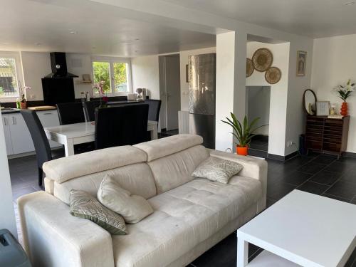 a living room with a white couch and a kitchen at Maison avec jardin, à deux pas de Paris in Deuil-la-Barre