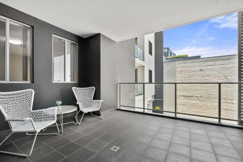 a balcony with chairs and a table and a glass railing at 38HP Abnb-Style Quality Hurlstone Park Free parking 2BR in Sydney