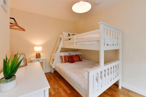 a bedroom with two bunk beds and a desk at Castle Square Cottage - Beachside Retreat in The Mumbles