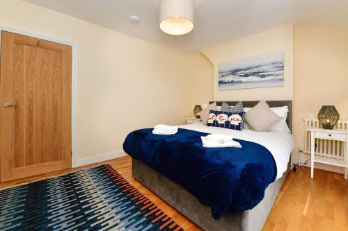 a bedroom with a large bed with a blue blanket at Castle Square Cottage - Beachside Retreat in The Mumbles