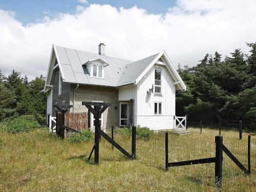une petite maison blanche dans un champ avec une clôture dans l'établissement 5 person holiday home in Harboøre, à Harboør