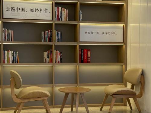 two chairs and a table in front of a book shelf at Hanting Hotel Beijing Wudaokou Tsinghua Park in Beijing