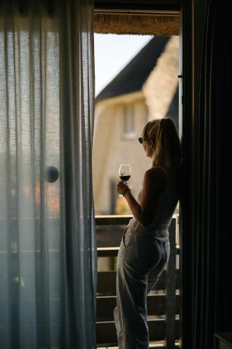 a woman holding a glass of wine looking out a window at Vlierijck in Oost-Vlieland