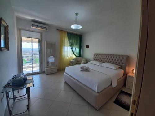 a bedroom with a large bed and a large window at Sunrise Apartment Rruga Qeret Kavaje in Kavajë
