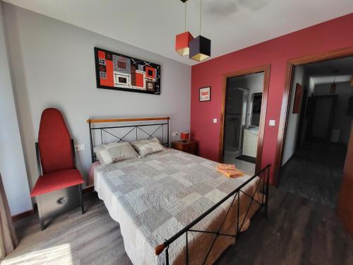 een slaapkamer met een bed en een rode muur bij Apartemento Cerveira in Vila Nova de Cerveira