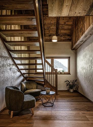a living room with a staircase and two chairs and a table at Naturhof eibl in Grossarl