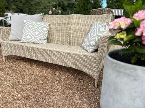 a wicker couch with pillows sitting on a patio at Weberhof-Münster 2 in Münster