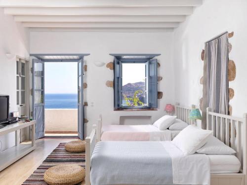 two beds in a bedroom with a view of the ocean at Patmos Eye Boutique Hotel & Villas in Skala