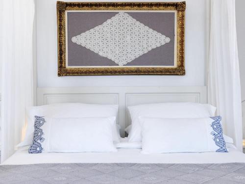 a bedroom with two white pillows and a picture on the wall at Patmos Eye Boutique Hotel & Villas in Skala