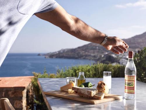 a man standing on a table with a bottle of wine at Patmos Eye Boutique Hotel & Villas in Skala