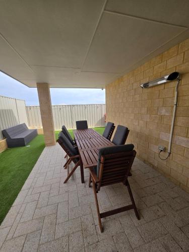 a patio with a wooden table and four chairs at Sandcastle by the Sea in Yanchep