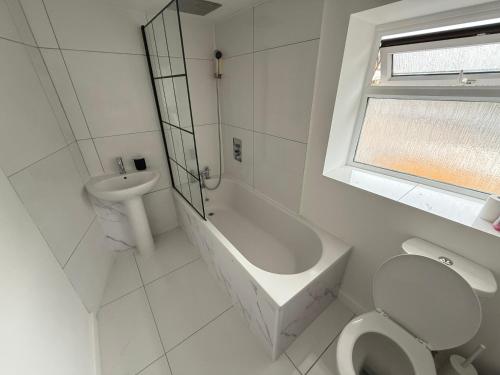 a white bathroom with a toilet and a sink at New 3 Bedroom Flat Close to Station in Chepstow