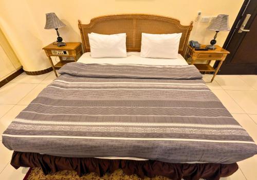 a large bed in a room with two night stands at Panoramic Hotel Lahore in Lahore