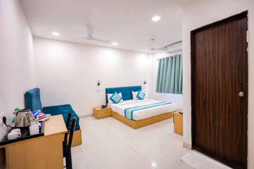 a bedroom with a bed and a desk and a door at Hotel Konark Nest-Vijay Nagar in Indore