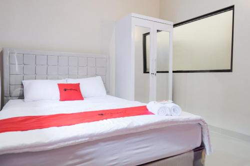 a white bed with red pillows and towels on it at RedDoorz Syariah near Hajimena Lampung in Lampung