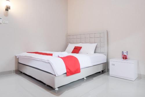 a white bedroom with a bed with a red blanket at RedDoorz Syariah near Hajimena Lampung in Lampung
