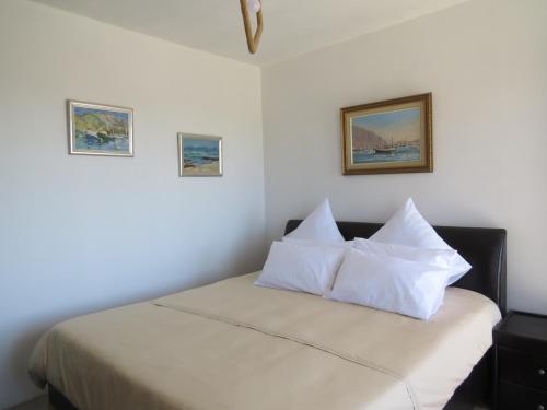 un dormitorio con una cama con sábanas y almohadas blancas en Island View Room, en Mossel Bay