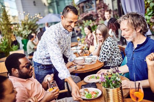 a group of people sitting around a table in a restaurant at Hotel Indigo Brussels - City by IHG in Brussels