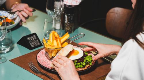 a person holding a sandwich and french fries on a table at Hotel Indigo Brussels - City by IHG in Brussels